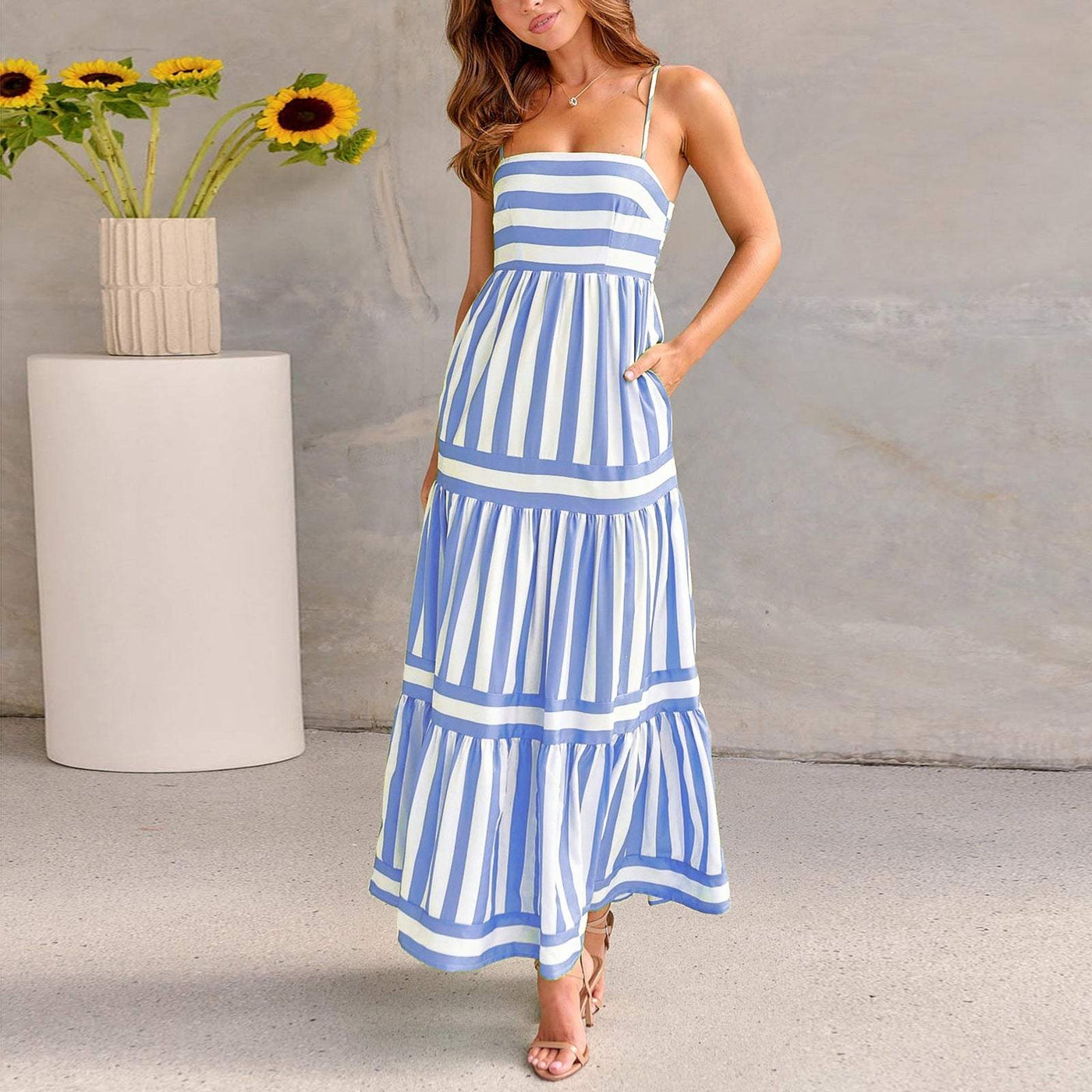Femme portant une robe longue à bretelles rayée bleue et blanche style plage élégante et fluide