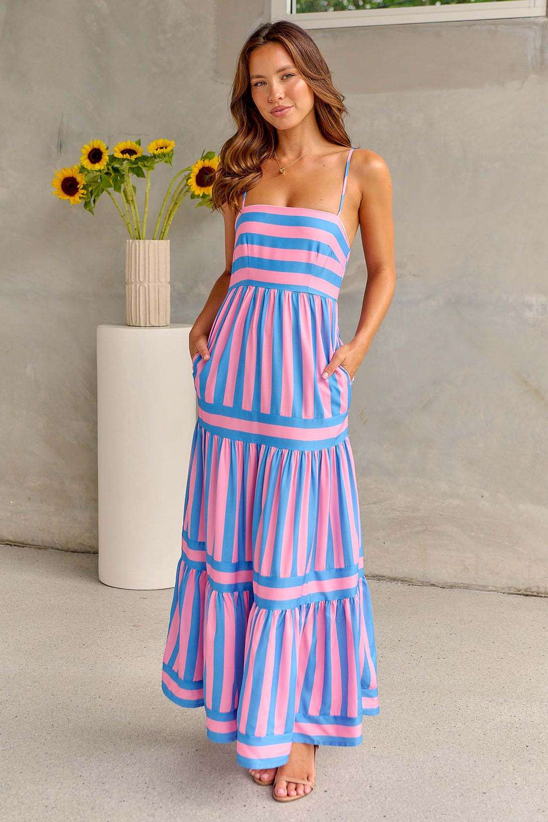 Femme portant une robe longue à bretelles rayée bleu et rose style plage