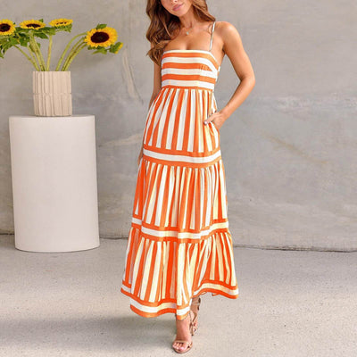 Femme portant une robe longue à bretelles rayée orange et blanche style plage, ambiance élégante et estivale.