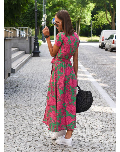 femme en robe de plage fluide à imprimé floral rose et vert avec ceinture nouée, style chic décontracté, baskets blanches et sac noir en ville