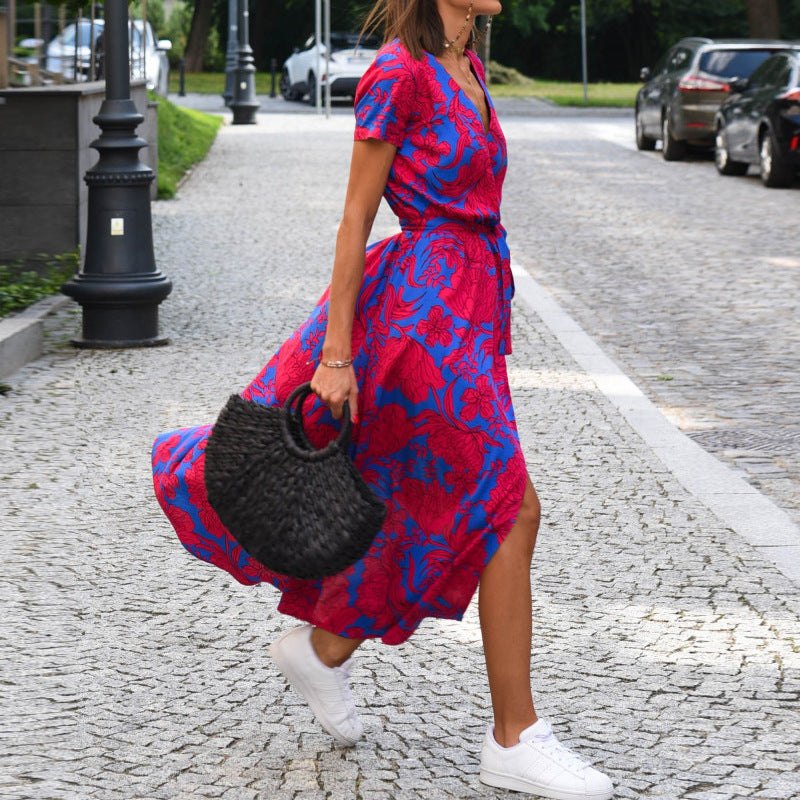 femme en robe de plage fluide imprimé floral rouge et bleu avec sac en paille noir et baskets blanches style chic décontracté