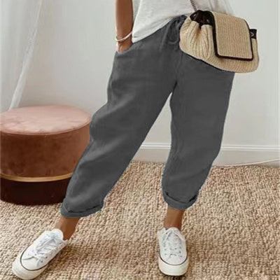 Pantalon décontracté uni gris pour femme en coton et lin, style épuré et confortable, porté avec basket blanche et sac beige tressé.