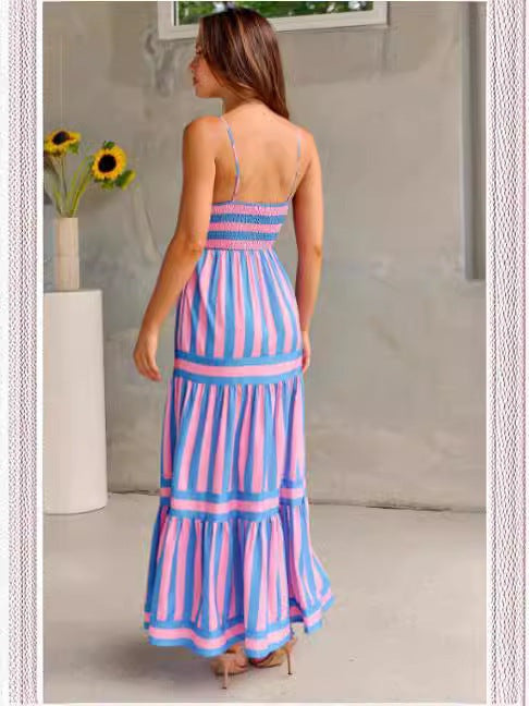 Femme portant une robe longue à bretelles rayée rose et bleu style plage vue de dos.